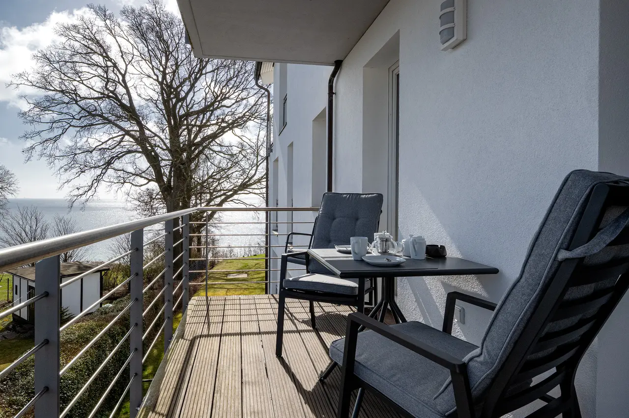 Fewo Seeblick Balkon mit Ostseeblick. Professionelle Immobilienfotos der Ferienwohnung Seeadler; stimmungsvolle Schlafzimmer-Beleuchtung im "Nordic Cozy"-Stil.
