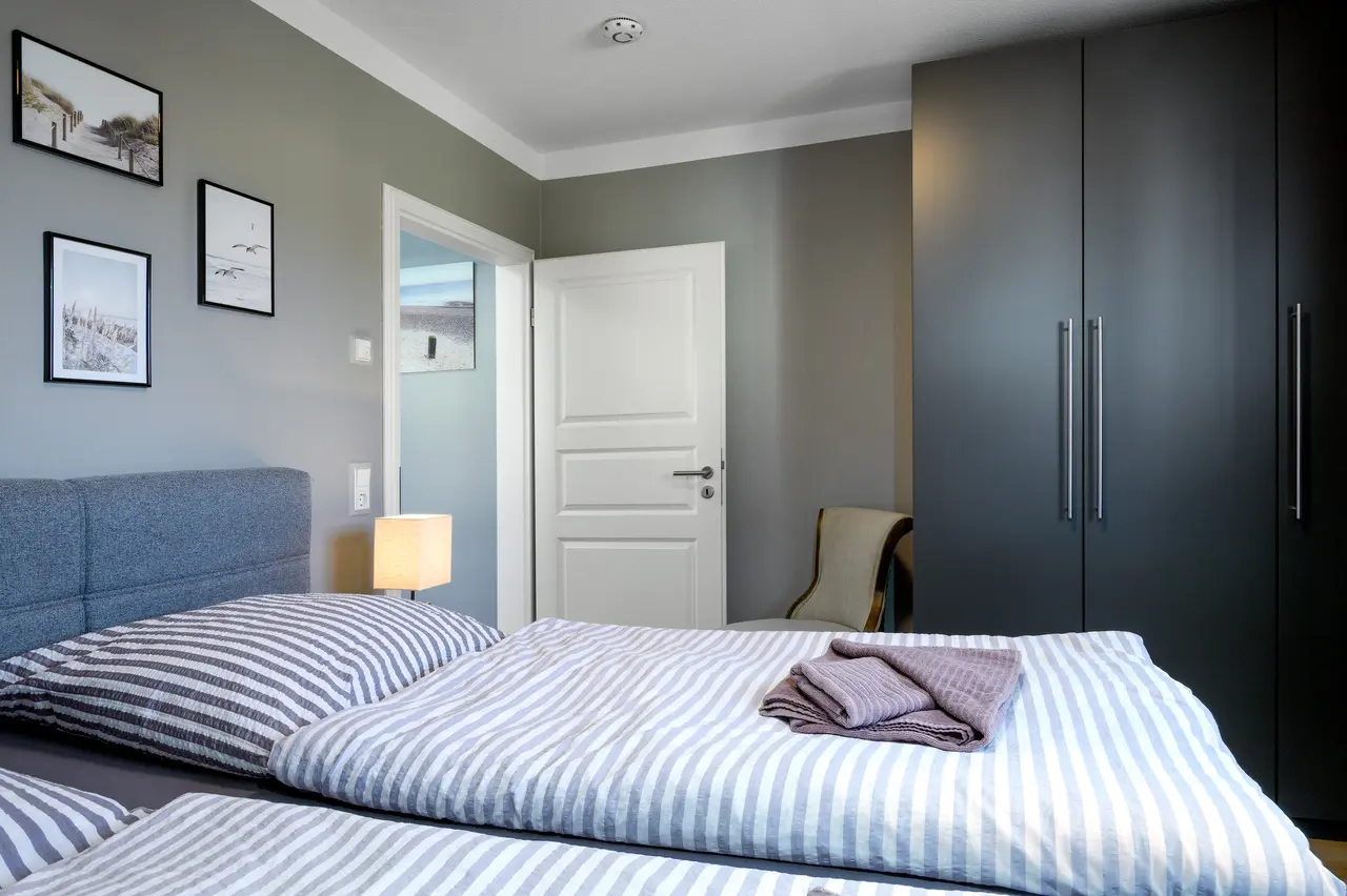 Fewo Seeblick Schlafzimmer. Professionelle Immobilienfotos der Ferienwohnung Seeadler; stimmungsvolle Schlafzimmer-Beleuchtung im "Nordic Cozy"-Stil.